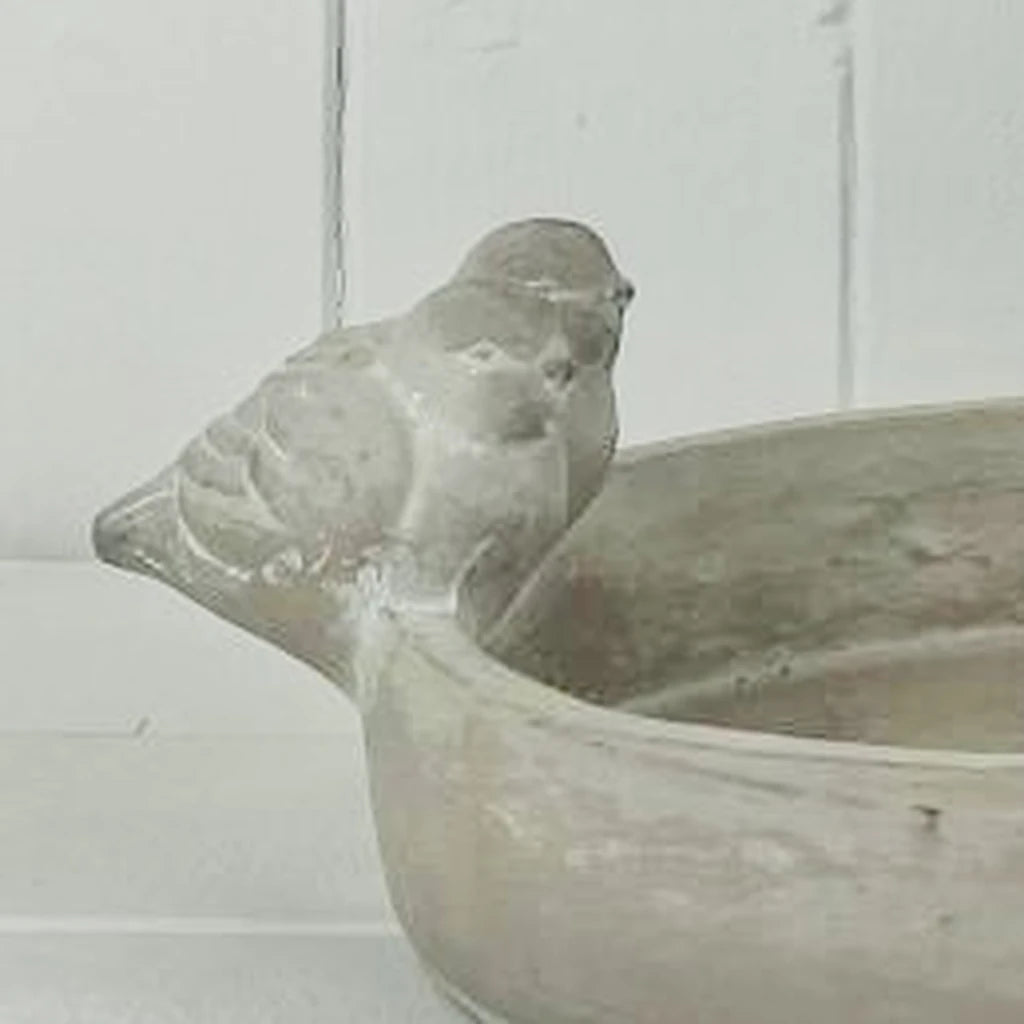 Close-up of the sculpted bird and weathered finish of the stoneware bird bath