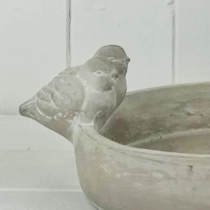 Close-up of the sculpted bird and weathered finish of the stoneware bird bath