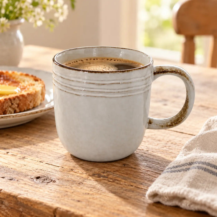 Stoneware coffee mug filled with coffee beside toast on a rustic breakfast table