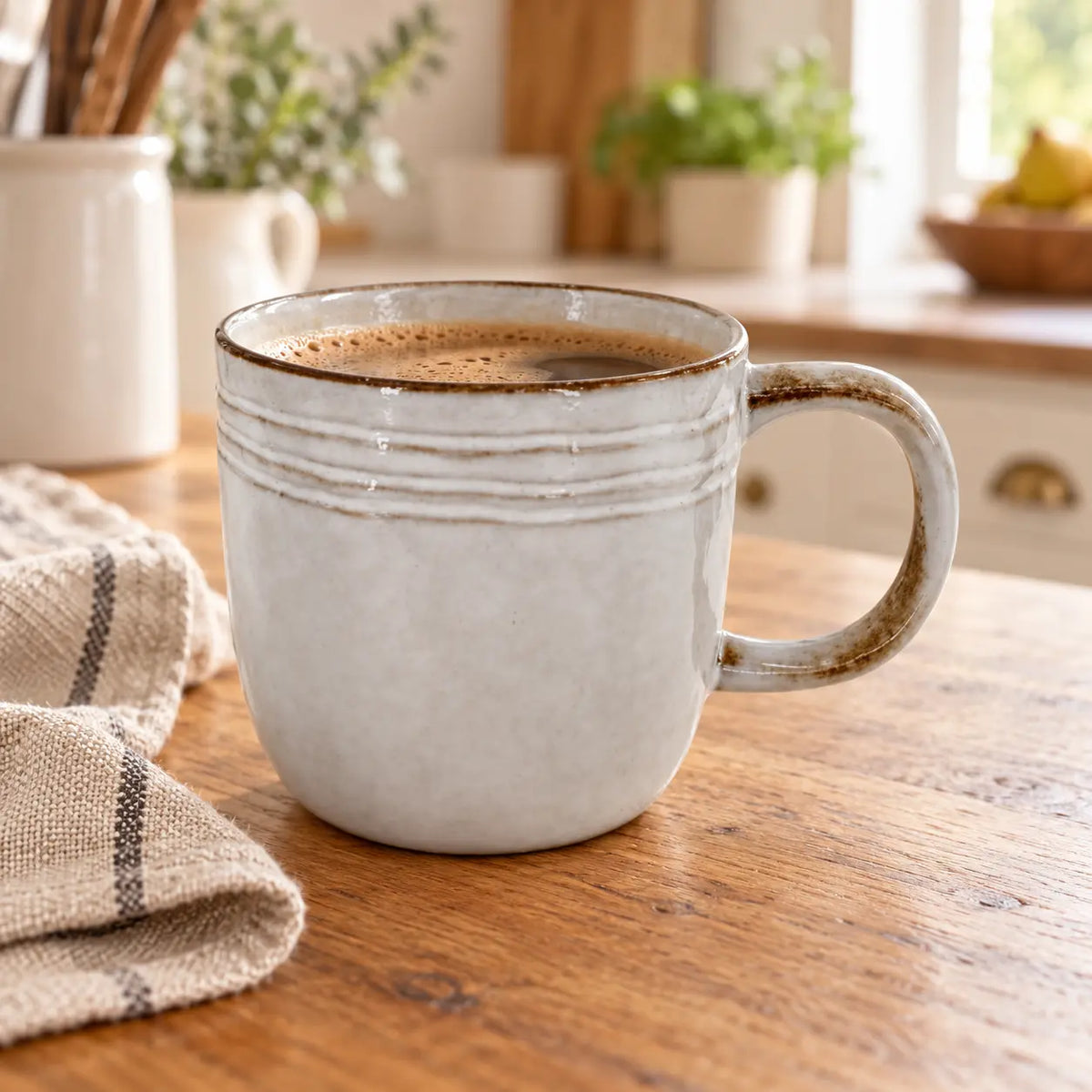 Pale stoneware coffee mug with brown rim on an oak counter in a light country kitchen