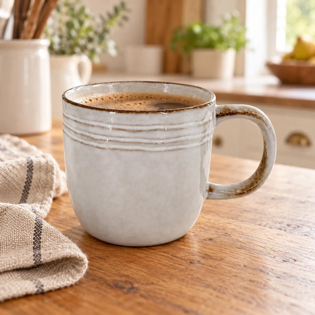 Pale stoneware coffee mug with brown rim on an oak counter in a light country kitchen