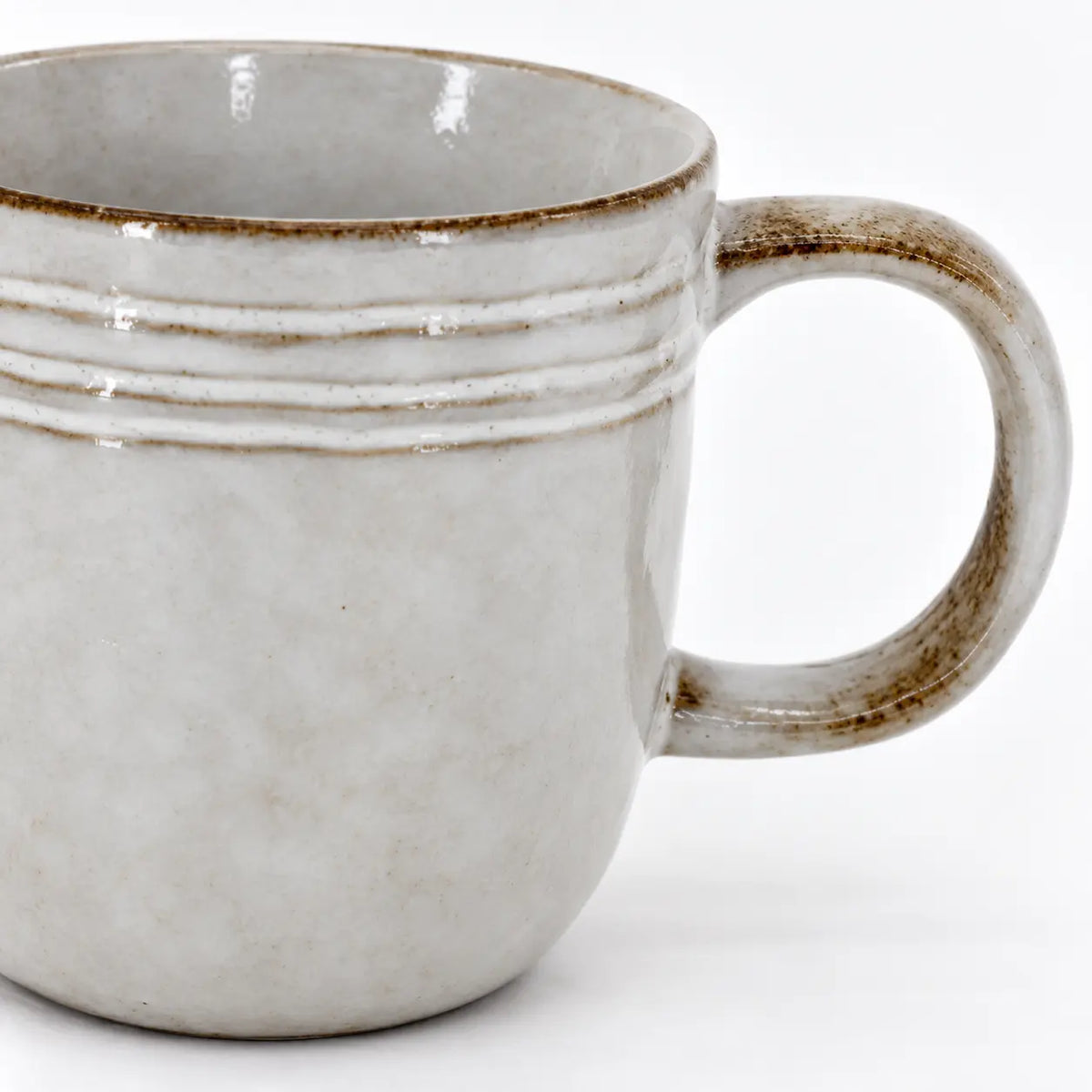 Close-up of the stoneware coffee mug's raised bands, brown rim and glazed handle