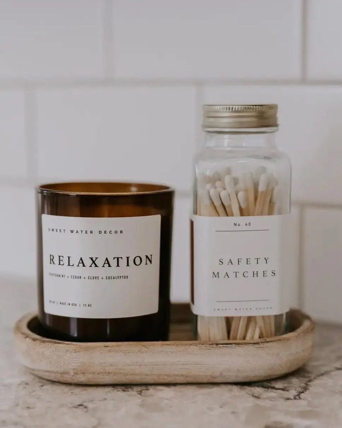Small glass jar from Sweet Water Decor with a white candle and matches, ideal for home decor and ambiance.