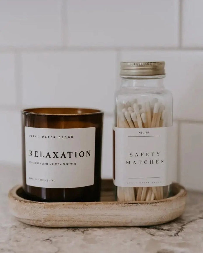 Small glass jar from Sweet Water Decor with a white candle and matches, ideal for home decor and ambiance.