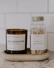 Small glass jar from Sweet Water Decor with a white candle and matches, ideal for home decor and ambiance.
