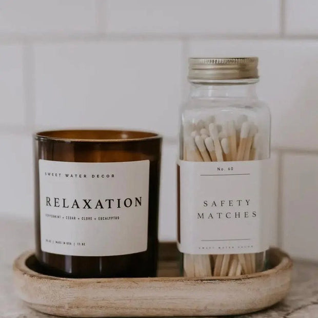 Small glass jar from Sweet Water Decor with a white candle and matches, ideal for home decor and ambiance.