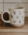 Cream glazed ceramic mug with brown leaf design by Sweet Water Decor, perfect for kitchen and dining use.