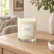 Heaven Scent Tea Tree And Geranium Medium Candle, ivory wax in clear glass on an oak console