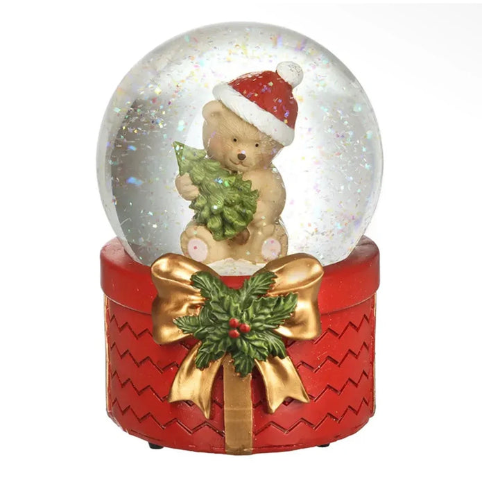 Teddy bear snow globe with red Santa hat, green tree and gold bow on white background