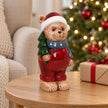 Red teddy bear Christmas ornament on an oak side table beside a wrapped gift
