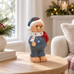 Blue teddy bear ornament with white scarf and red detail beside a bright window