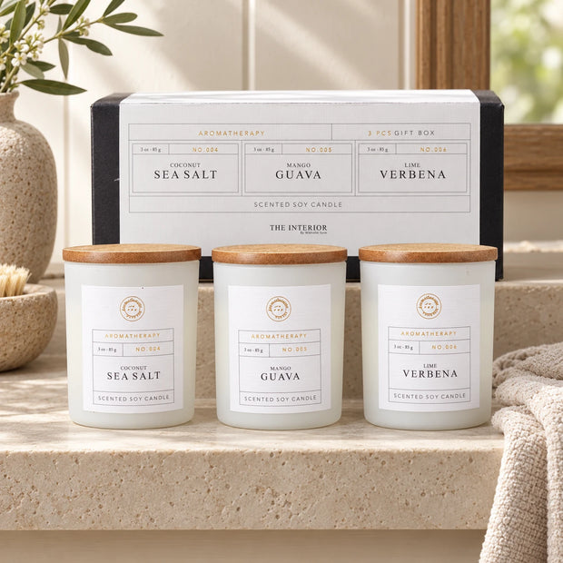 Therapy Candles Gift Set - Set Of Three — Three closed jars on pale stone bathroom shelf with original box behind and soft linen towel aside