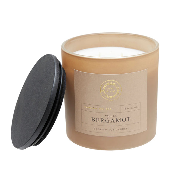 Vanilla and bergamot candle in a beige pot with its lid beside it