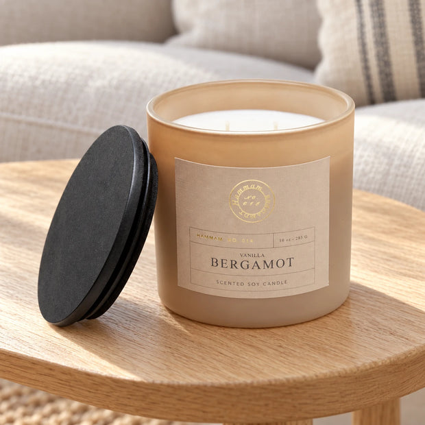 Vanilla And Bergamot Candle — Unlit candle and lid on pale oak side table