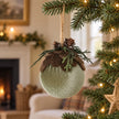 Green velvet woodland bauble hanging on a Christmas tree.