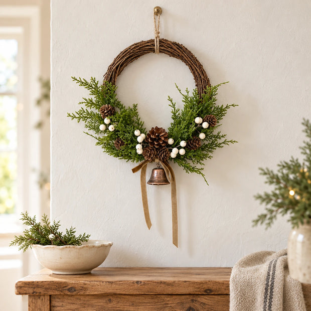 Medium Satchville Christmas twig wreath with white berries, pinecones, bells, and a bow for festive wall decor.