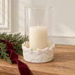 White bow hurricane candle holder with unlit ivory candle on an oak Christmas console