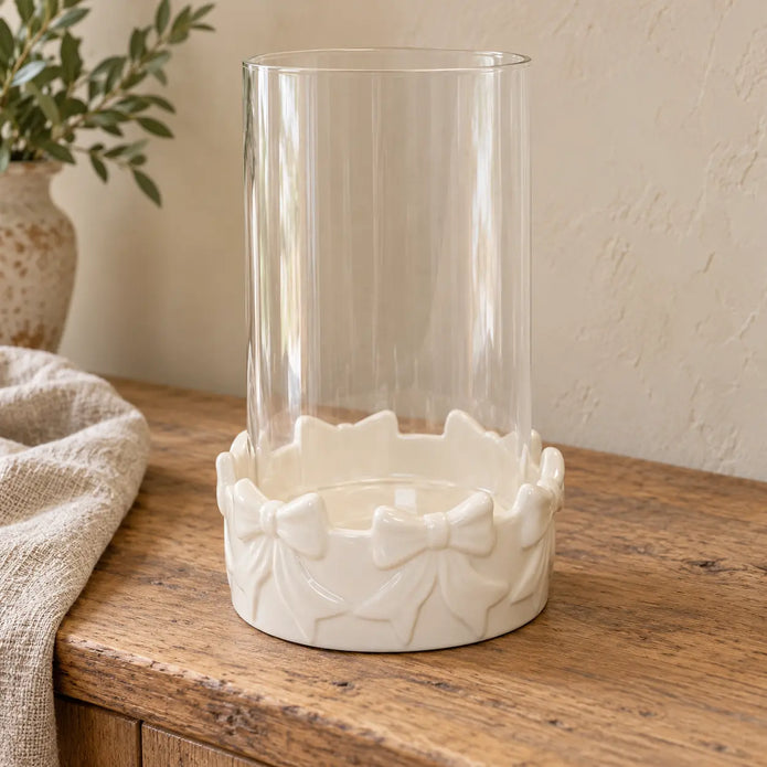 Empty white bow ceramic candle holder with clear glass insert on a rustic sideboard