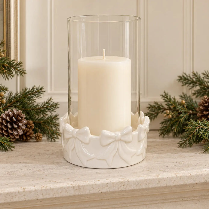 White ceramic bow hurricane with unlit pillar candle on a pale stone mantel