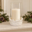 White ceramic bow hurricane with unlit pillar candle on a pale stone mantel