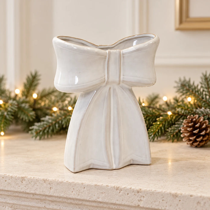 Large white ceramic bow-shaped vase displayed empty on a neutral Christmas mantel