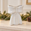 Large white ceramic bow-shaped vase displayed empty on a neutral Christmas mantel
