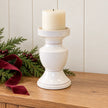 Large white ceramic candle holder with unlit ivory pillar candle on an oak Christmas console