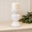 White ceramic pedestal candle holder with unlit candle on a pale stone mantel