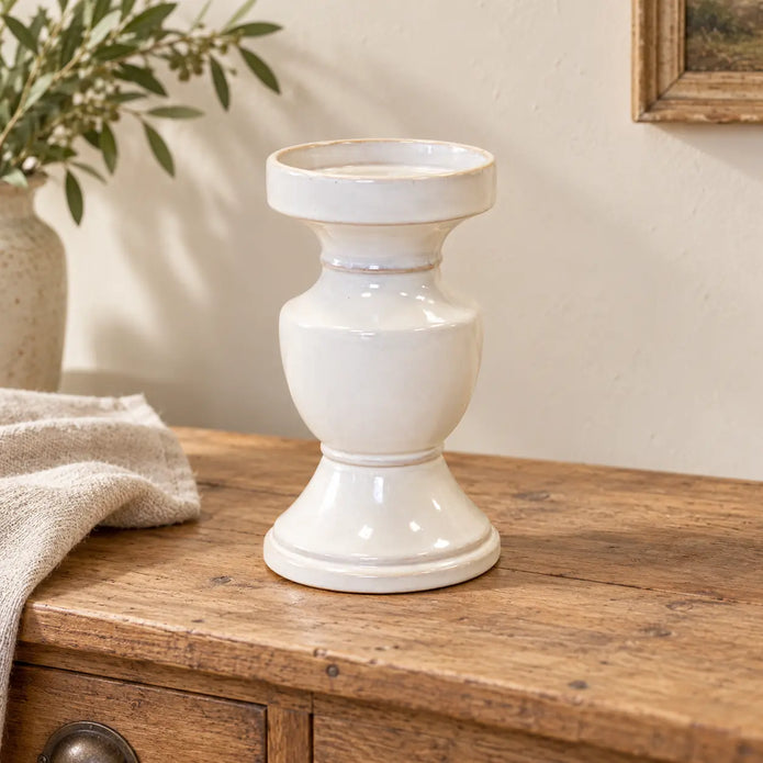 Large white glazed ceramic candle holder displayed empty on a rustic sideboard