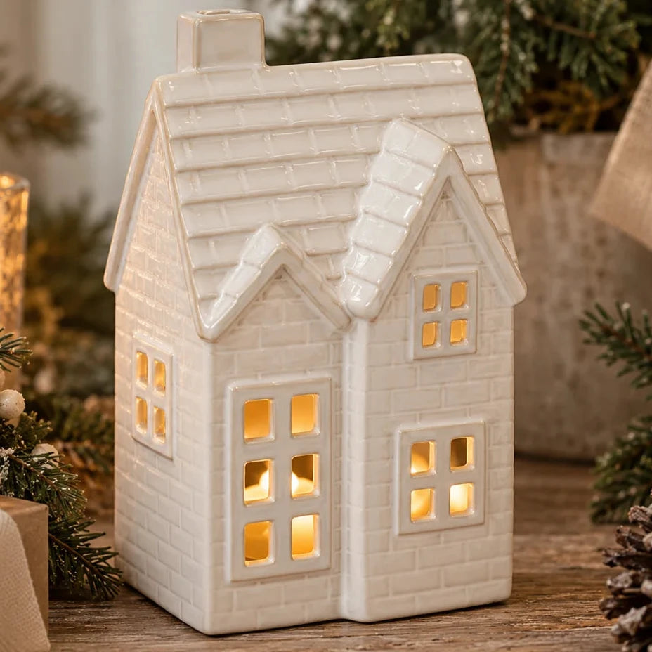 Medium glazed ivory ceramic tiled LED Christmas house with illuminated windows, styled with spruce and neutral decorations