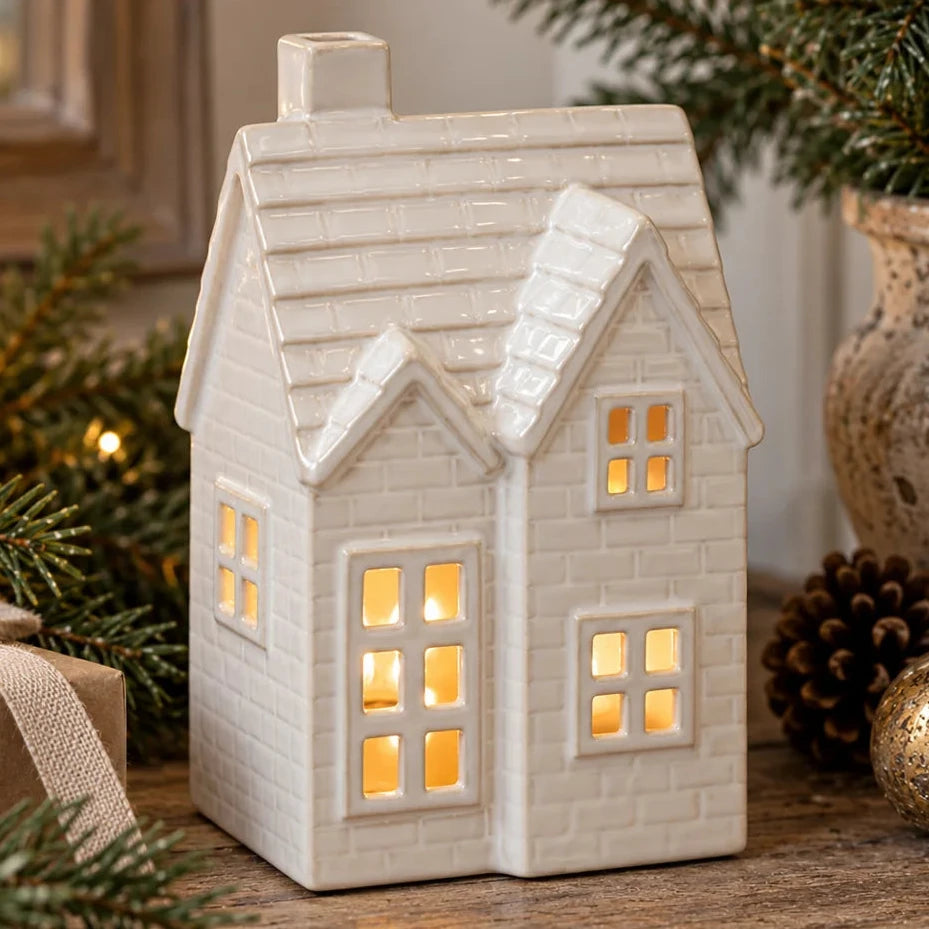 Cream ceramic LED Christmas house with pitched tiled roof and glowing windows in a rustic festive display