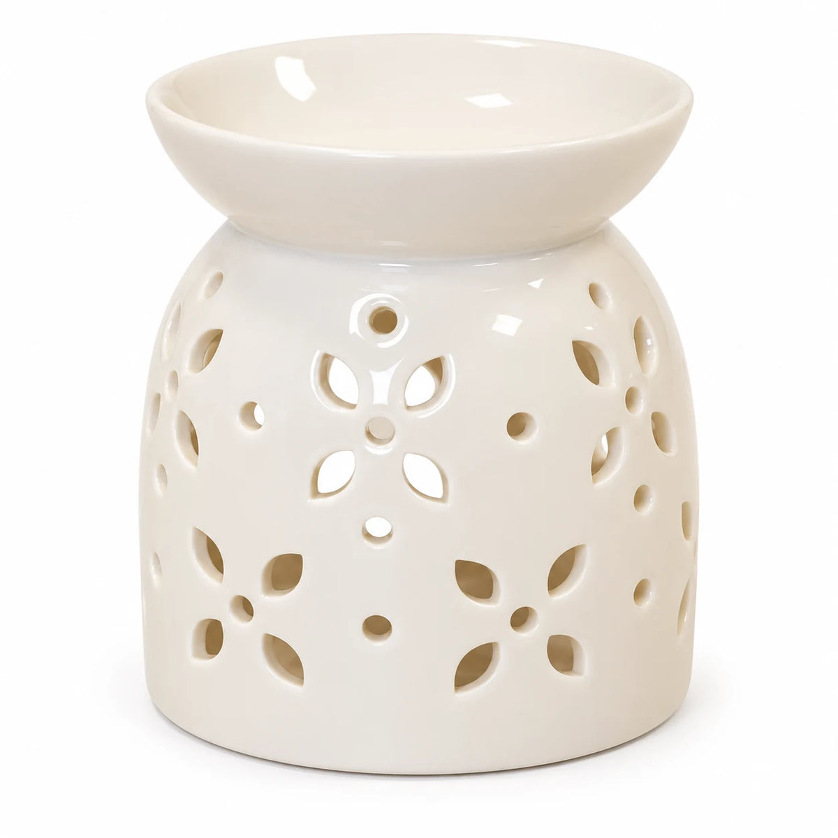 Close studio view of flower-petal cut-outs and glossy white ceramic oil burner