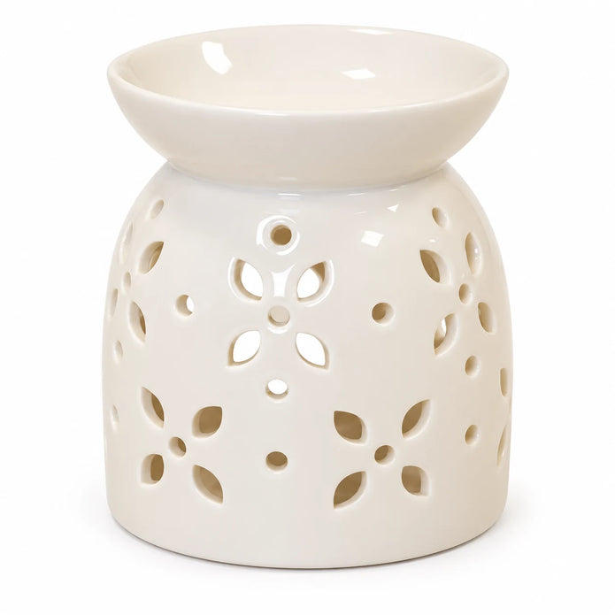 Close studio view of flower-petal cut-outs and glossy white ceramic oil burner