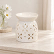 White ceramic flower-petal oil burner on a pale stone console in an everyday neutral room