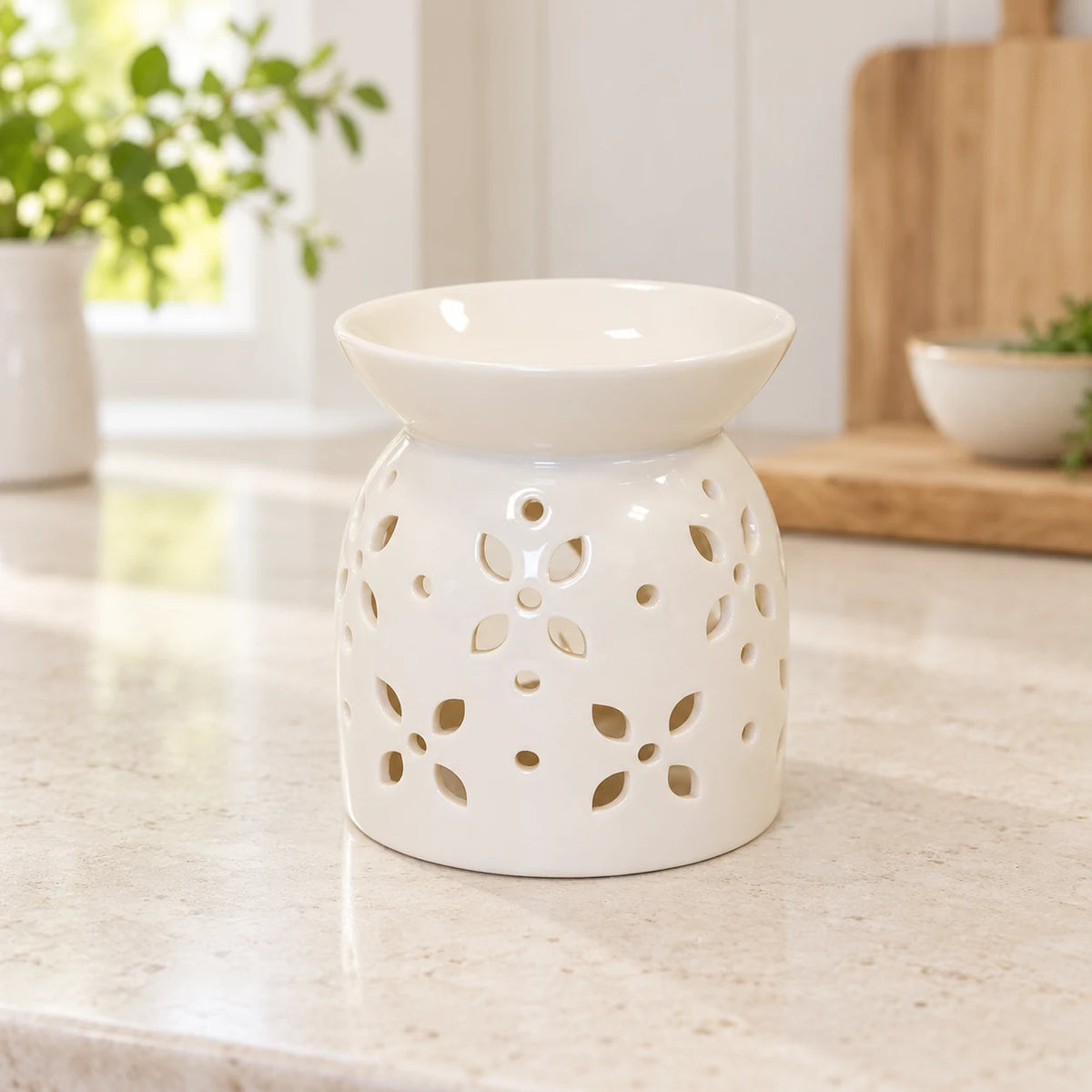 White glazed flower-petal oil burner displayed empty in a bright cream kitchen