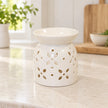 White glazed flower-petal oil burner displayed empty in a bright cream kitchen