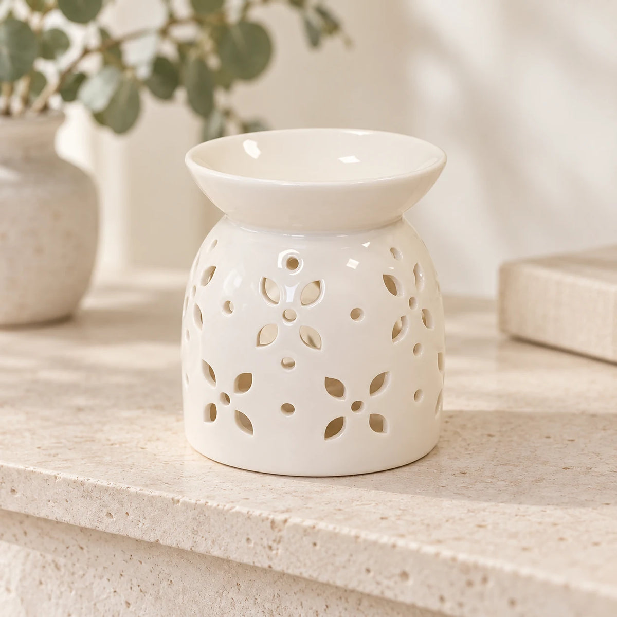 White ceramic petal oil burner on a light stone shelf with neutral everyday styling