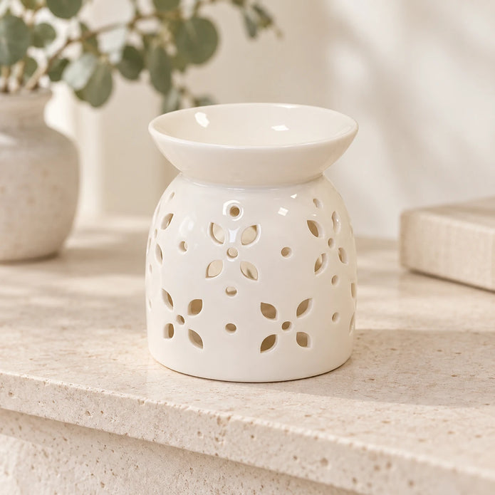 White ceramic petal oil burner on a light stone shelf with neutral everyday styling