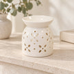 White ceramic petal oil burner on a light stone shelf with neutral everyday styling