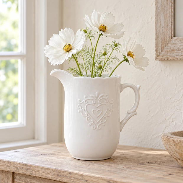 White ceramic heart jug styled with white faux cosmos on an oak console