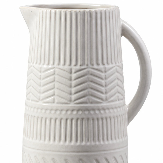 Close-up of the white ceramic jug’s vertical ribbing, chevron relief and small dotted band.