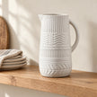 27cm white patterned ceramic jug displayed empty on an oak kitchen shelf.