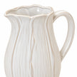 Close-up of the large white ceramic jug's scalloped petal rim and glazed handle