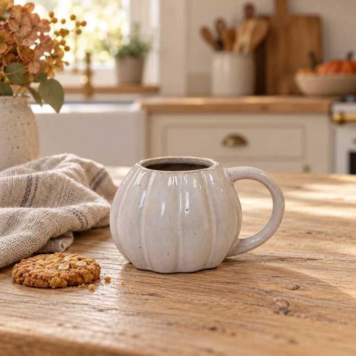 White ceramic pumpkin mug from Satchville with autumn-themed design, perfect for cozy kitchen decor and seasonal beverages.