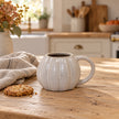 White ceramic pumpkin mug from Satchville with autumn-themed design, perfect for cozy kitchen decor and seasonal beverages.