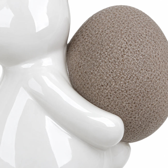 Large white ceramic rabbit holding a taupe egg, 21cm tall, white studio close-up of the glossy paw and textured egg.