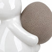 Large white ceramic rabbit holding a taupe egg, 21cm tall, white studio close-up of the glossy paw and textured egg.