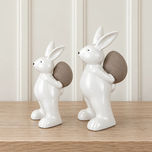 Small white ceramic rabbit holding an egg, perfect for spring decor, by Satchville.