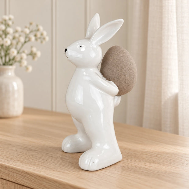 Small white ceramic rabbit holding an egg, perfect for spring decor, by Satchville