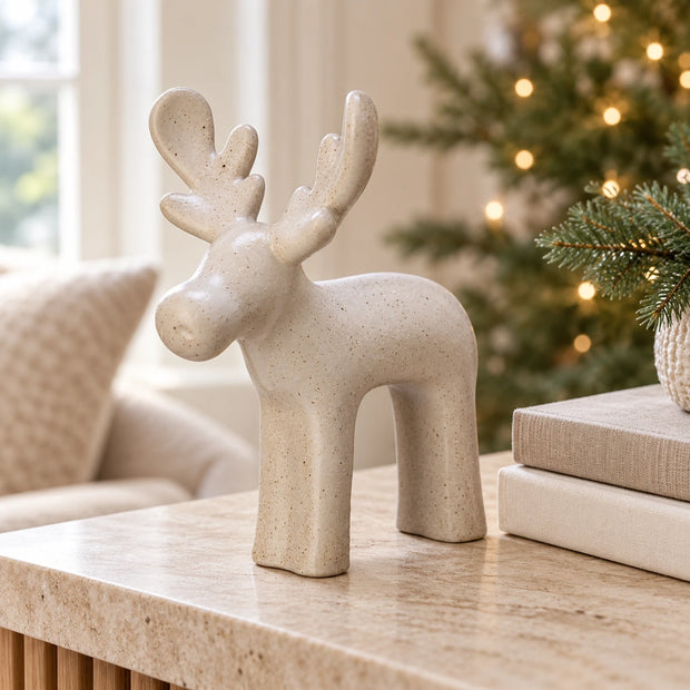 White Ceramic Reindeer — One reindeer on pale stone console beside two neutral books
